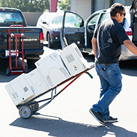 "man carting around old printers on a dolly"