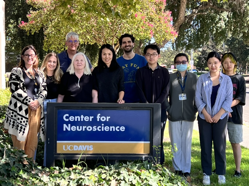 Dr. Xiaomo Chen and her lab group standing behind the UC Davis Center for Neuroscience sign.