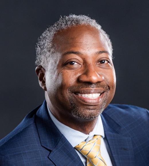 Headshot of Dr. Paisley in suit smiling at camera.